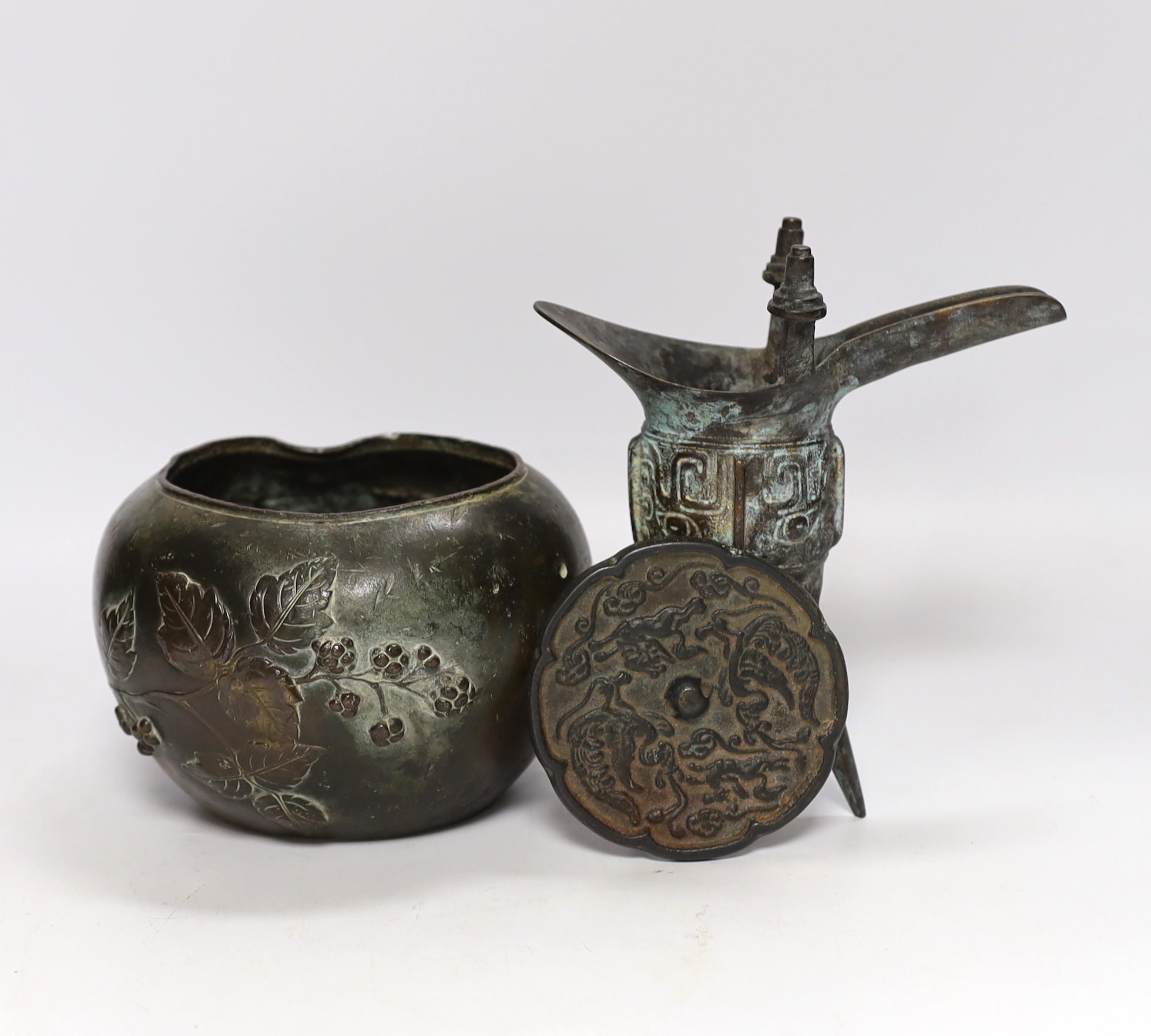 Three Chinese bronze items including a mirror back and a three footed cup, largest 18cm high